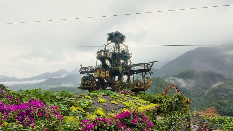 A unique treehouse-style structure surrounded by flowers and misty mountains in Sapa Vietnam